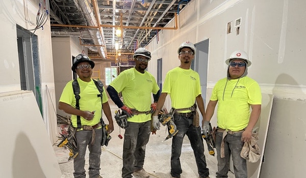 A group of construction workers pose while wearing their custom t-shirts. 