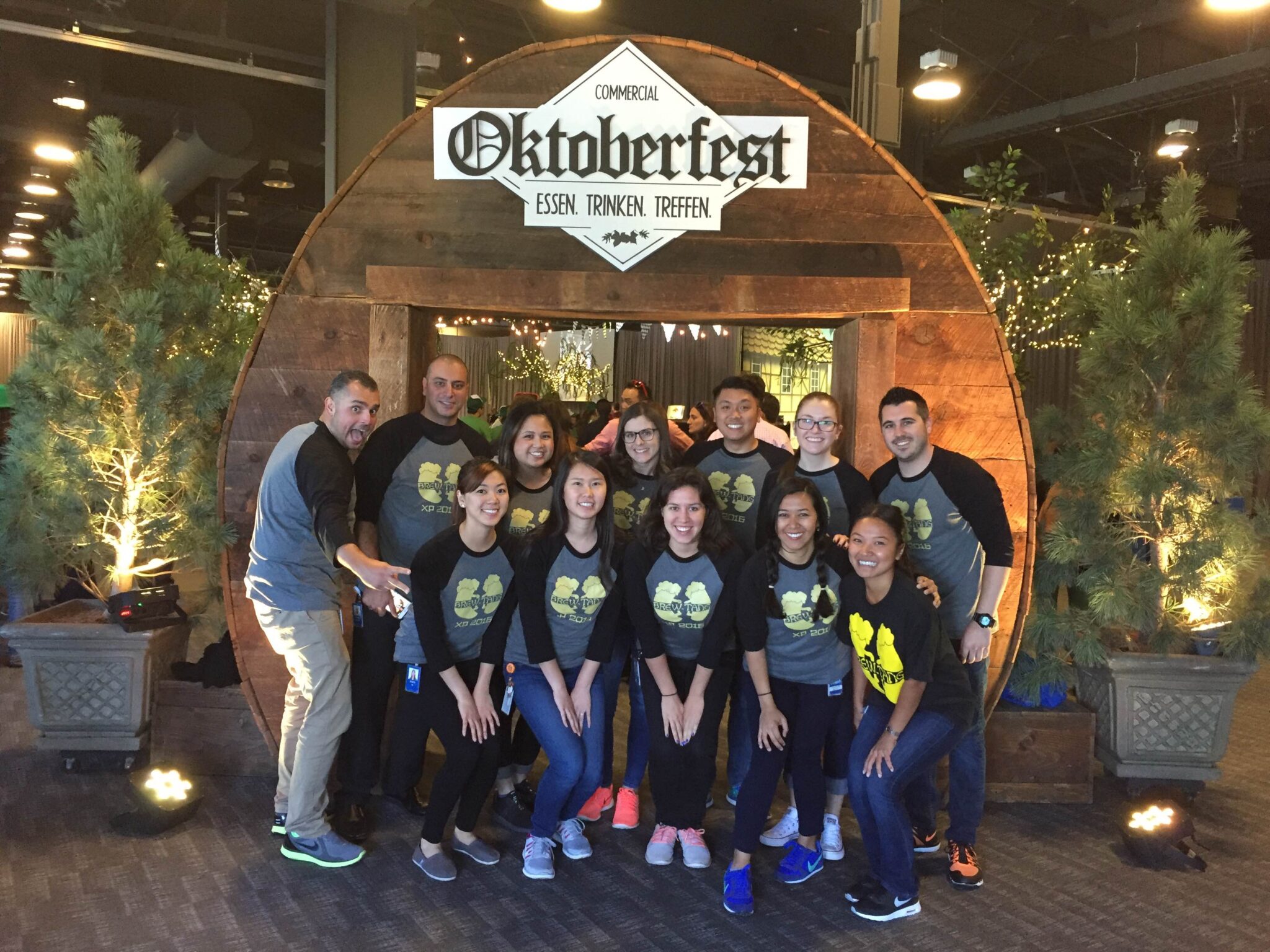 A group of friends stand at the entrance of an Oktoberfest event wearing matching t-shirts.