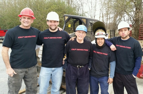 A group of construction workers pose while wearing their custom t-shirts. 