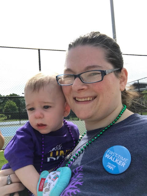 Woman holding her son at a fundraiser walk wearing custom t-shirts