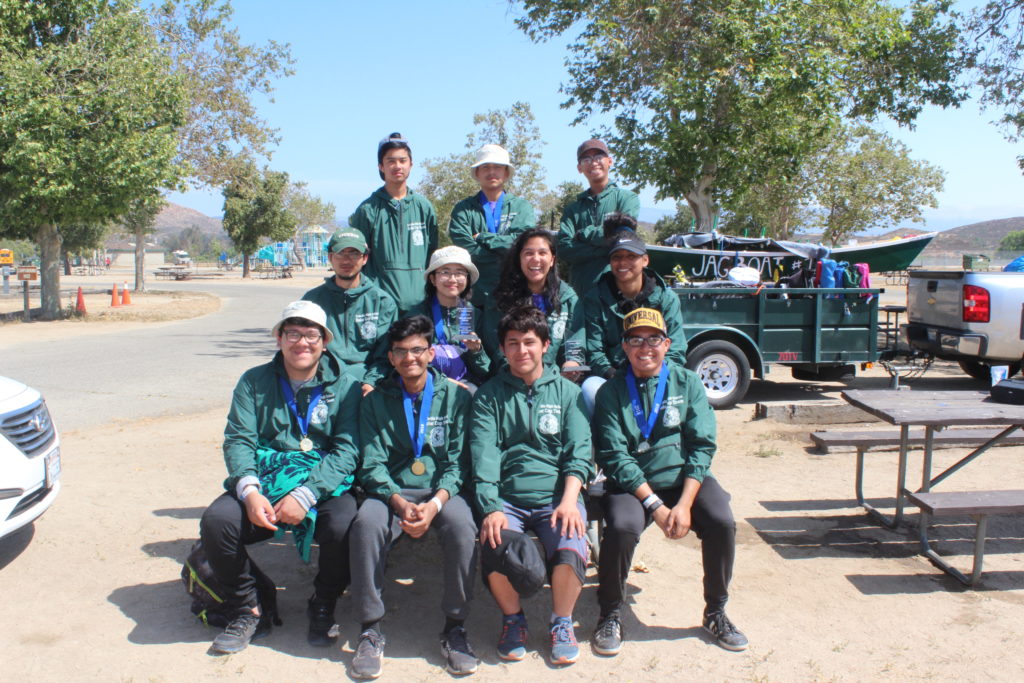 A team of students show off their custom team shirts after competing in an engineering competition.