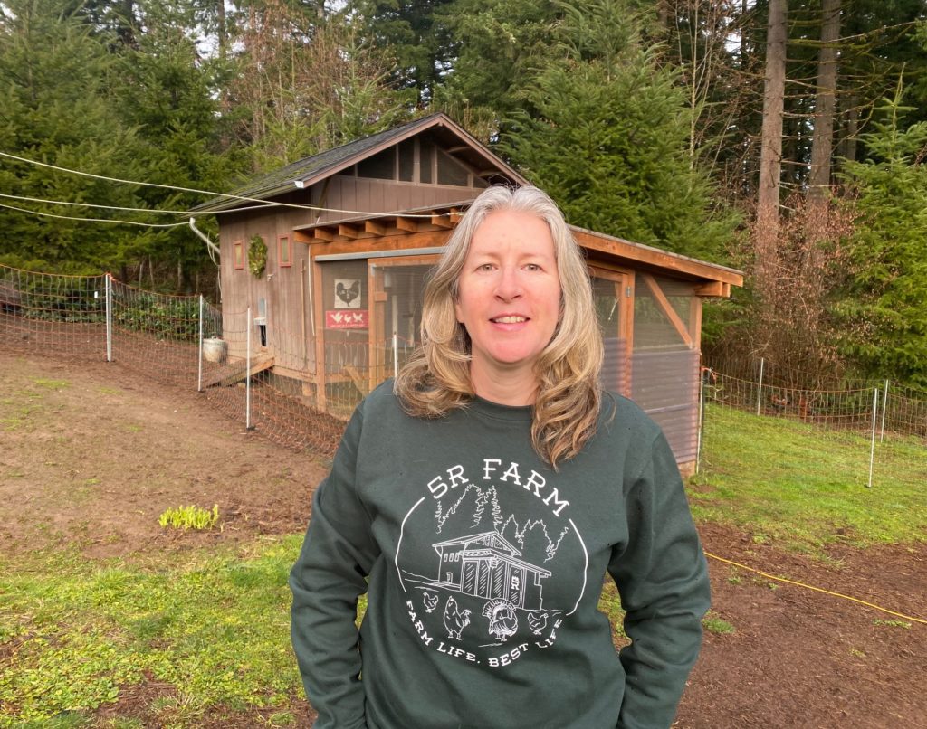 Stacy standing in front of one of the coops at 5R Farm wearing her custom shirt. Shirt is Hanes Comfort Garment Dyed Long Sleeve T-shirt