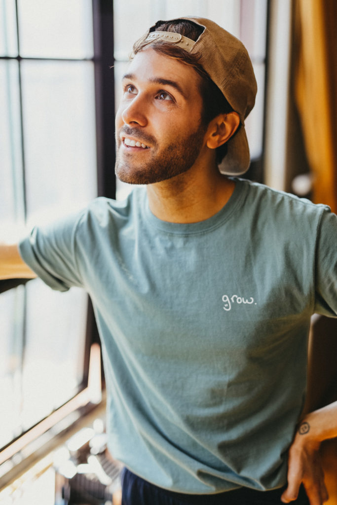 Tyler modeling his "grow." custom merch on a Hanes Comfort Garment Dyed T-shirt