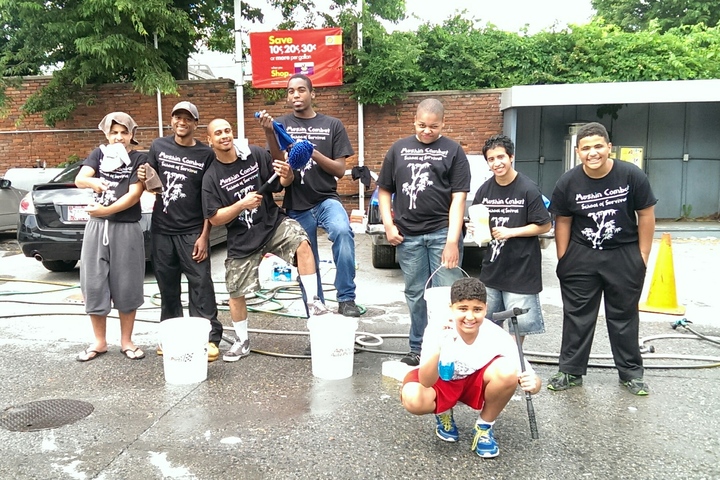 A grou-p of young men show off their custom t-shirts at a car wash fundraiser.