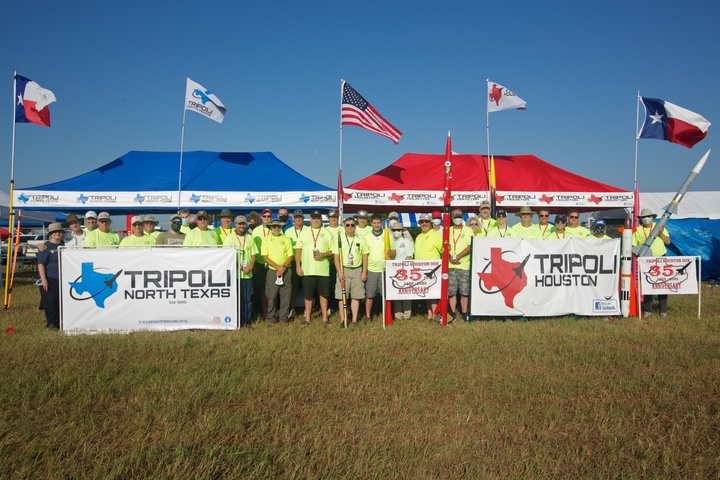 A large group of rocket hobbyists gather wearing custom t-shirts.