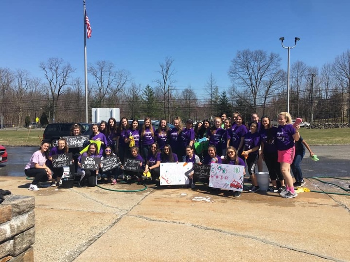 A group of kids wearing matching custom t-shirts at a car wash fundraising event