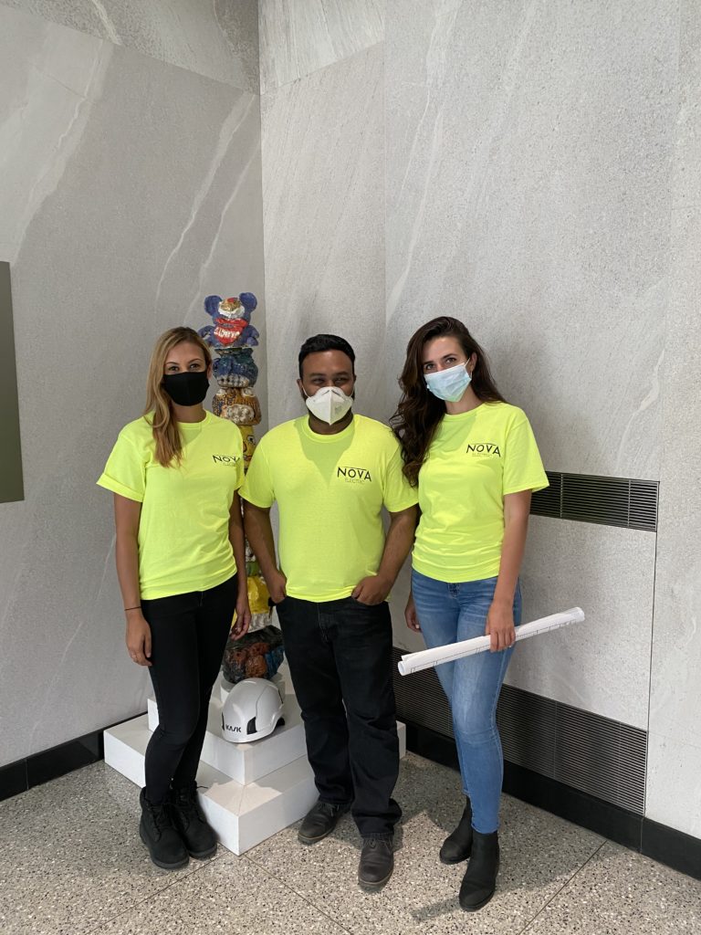 Three people pose while wearing matching neon green shirts that have Nova Electric printed on them.