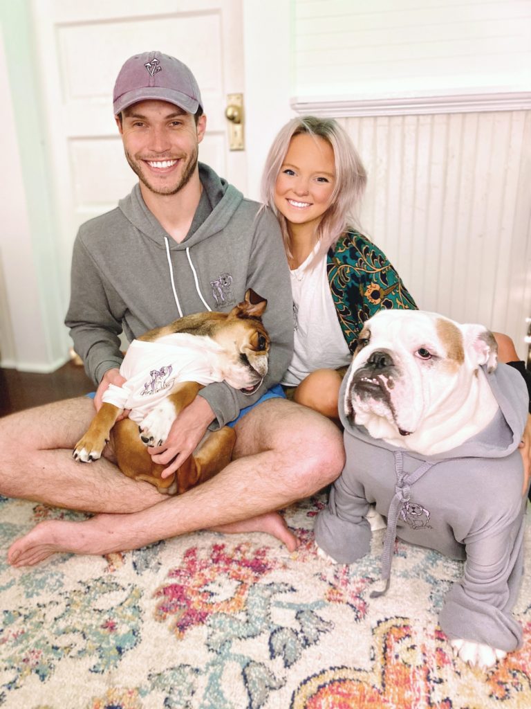 A man, woman, and their two bulldogs sitting down and posing