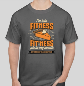 A gray t-shirt that reads "I'm into fitness—fit'ness pie in my mouth" in orange text. On a brown banner below, it reads "Lee Family Thanksgiving." In the center, there is a glowing piece of pumpkin pie with a dollop of whipped cream.