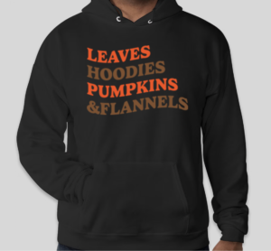 A black unisex hoodie with the list "Leaves hoodies pumpkins & flannels" in orange and brown ink colors.