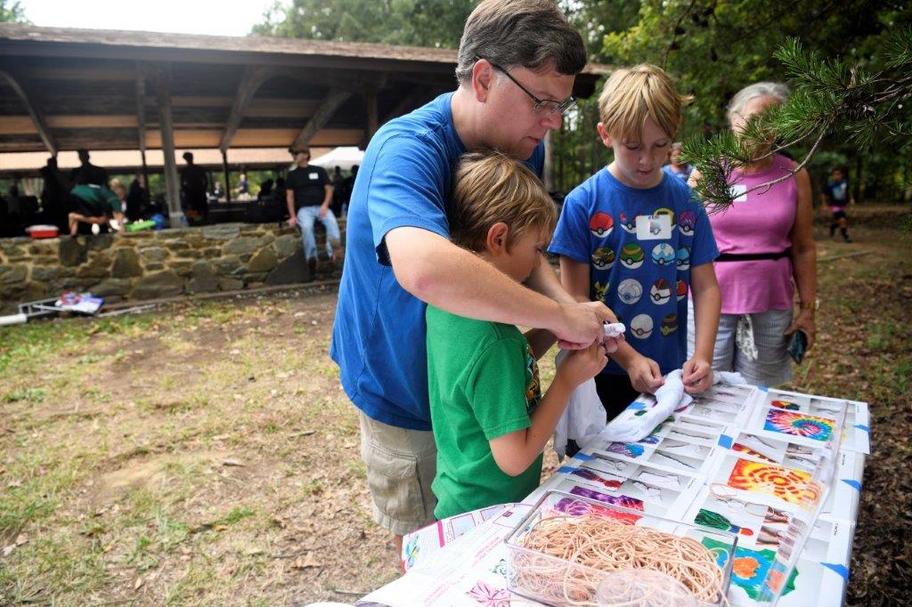 A man and two children stand at the tie-dye table