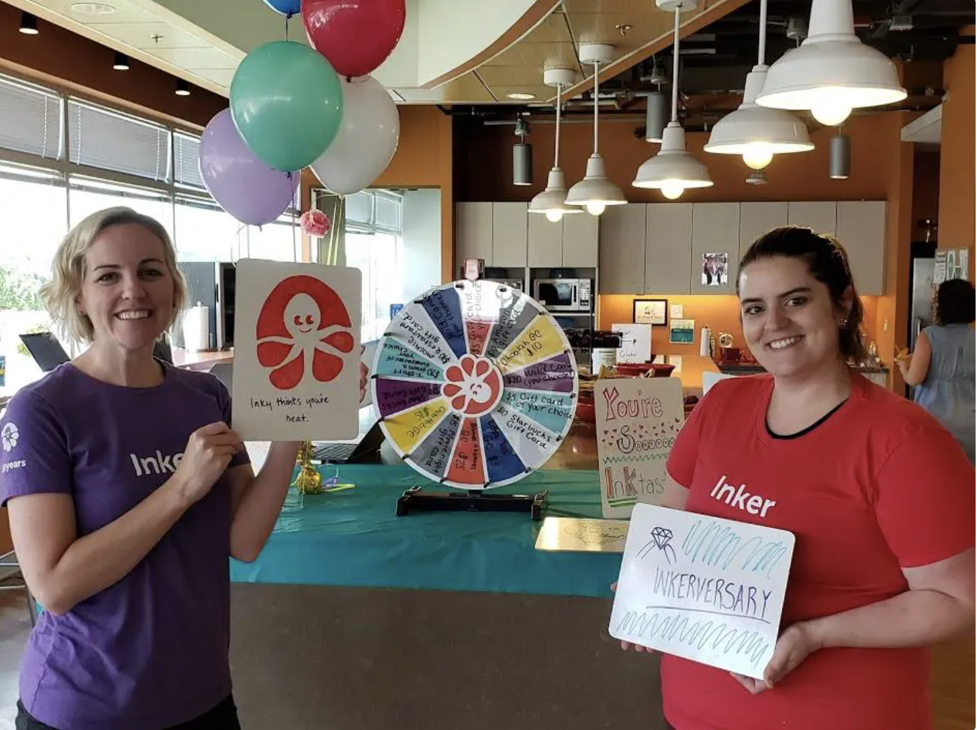 Two Custom Ink team members in their custom shirts show off rewards for employee tenure.