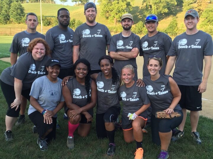 A payroll team wear shirts that say "Death & Taxes" for a softball game.