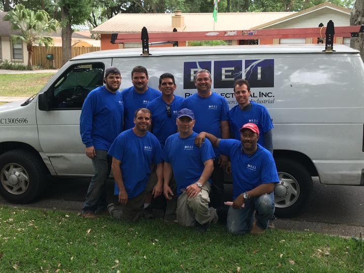 Rick's Electrical Inc. team pose in front of their work van wearing custom gear. 
