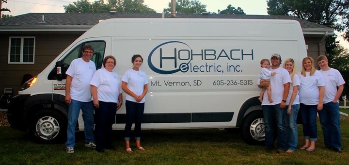 The Hohbach Electric, Inc. team pose in front of their work van wearing custom gear. 