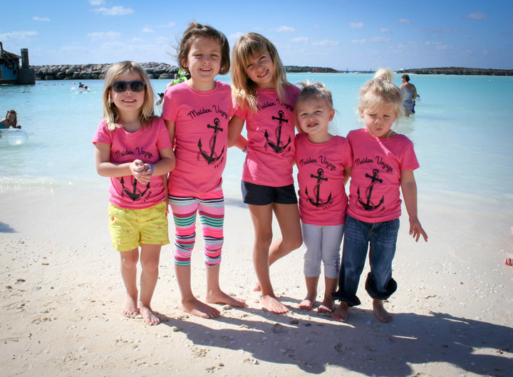 A group of kids on a beach wear pink shirts that say "Maiden Voyage."