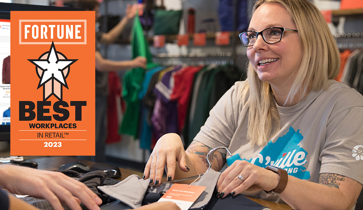 An image of a Custom Ink employee assisting a customer in choosing a product. An award for Fortune's Best Workplaces in Retail in 2023 is overlaid on the image.